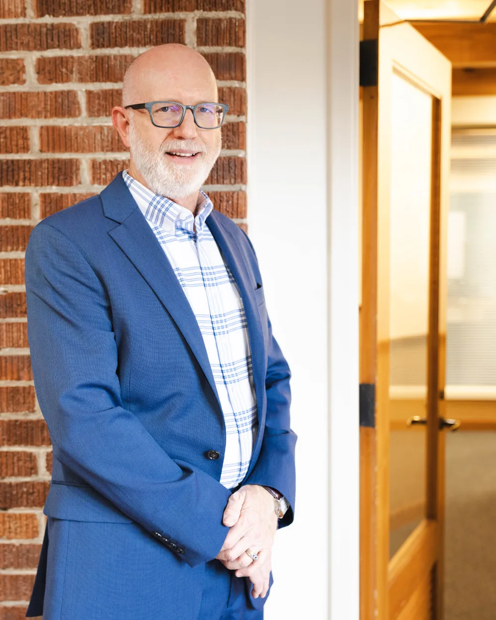 David M. Butterbaugh, San Antonio estate planning attorney, standing by a brick wall in his office